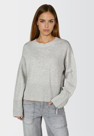 Hellgrauer, kürzer geschnittener Pullover mit geripptem Saum und Bündchen. Weicher Stoff, runder Halsausschnitt und lange Ärmel. Kombiniert mit hellgrauen Jeans.