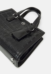 Black handbag with crocodile texture, dual handles, and snap closure. Features metallic logo and polished hardware accents.