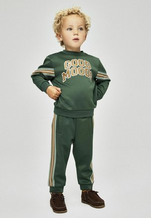 Tuta sportiva verde con testo "GOOD MOODS" sulla felpa e dettagli a strisce sui pantaloni. Tessuto testurizzato e polsini aderenti.