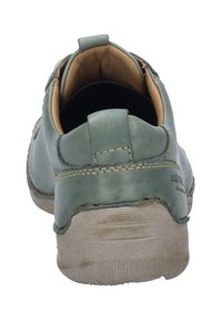 Scarpa in pelle verde con un retro arrotondato, dettagli cuciti e una suola piatta e testurizzata. L'interno è color nocciola con un colletto imbottito.