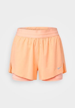 Short de course Nike couleur pêche avec couche de compression intégrée, taille élastique, fentes latérales et petit logo réfléchissant sur la jambe droite à l’avant.