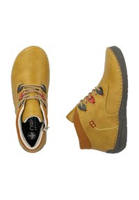 Bottes chelsea en cuir jaune avec semelles en caoutchouc gris, dotées de lacets colorés, d'accents bruns côtelés et de détails cousus.