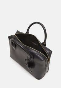 Musta nahkainen käsilaukku, jossa on vetoketjusuljenta, pyöreät kahvat ja pehmeä sisusta. Siinä on kullanvärinen vetoketju ja bränditunniste sisäpuolella.