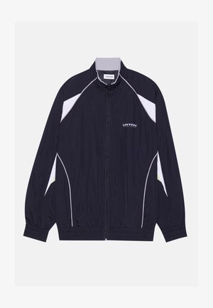 Marineblauwe jas met witte en limoengroene accenten, ritssluiting aan de voorkant, elastische manchetten en zoom, lichtgewicht materiaal en een sportief ontwerp.