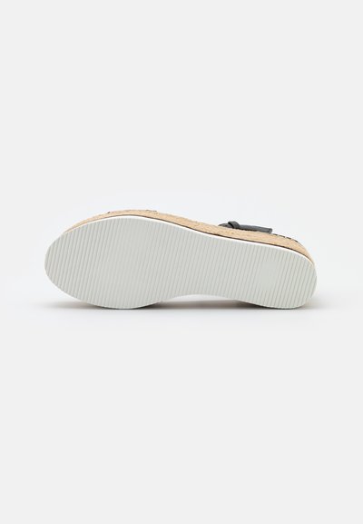 Kilesandal med kork- og gummisåle, teksturert beige overflate, svart justerbar stropp og hvit rillet yttersåle for grep.