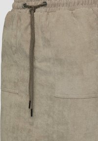 Beige corduroy joggers met een elastische tailleband, trekkoordsluiting en twee zijzakken. Heeft een gestructureerde stof en een subtiele glans.