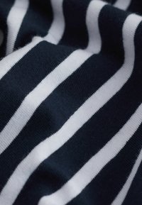 Marinblå och vit randig tyg med en mjuk textur. Ränderna är jämnt fördelade och skapar ett enhetligt mönster över materialet.
