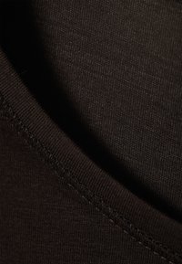 Melna auduma ar gludu tekstūru un vieglu elastību, ar apaļu kakla izgriezumu un ciešu šuvju detaļu gar malām.