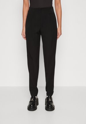 Sorte skreddersydde bukser med et glatt stoff, tapered design og frontplisséer. Båret med chunky svarte plattform sko.