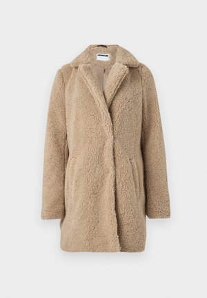 Beige teddy takki, jossa on kaulus, kaksirivinen etumus, sivutaskut ja tekstuuri, joka on pörröinen.
