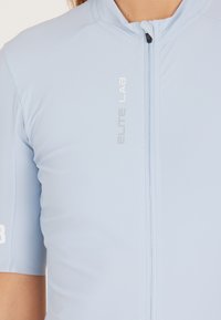 Lichtblauwe fietsjersey met korte mouwen, gemaakt van glad materiaal, met een rits aan de voorkant en het "ELITE LAB"-logo in zilver op de borst.