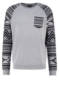 Sudadera gris con mangas largas negras estampadas, un bolsillo en el pecho con un diseño geométrico y puños y dobladillo acanalados.