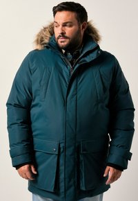 Giacca puffer color teal con cappuccio foderato in pelliccia, zip frontale e tasche con bottone a pressione. Presenta un tessuto isolante e polsini per il calore.