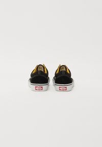 Juodi su suede pagaminti suplokšti batai su geltonu pamušalu ir baltu guma padais. Savybė - raudonas Vans logotipas ant kulno ir kontrastingos siūlės.