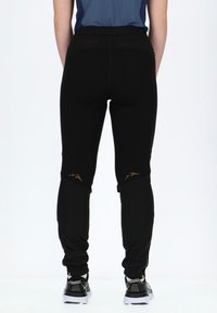 Black athletic pants with a slim fit, featuring gold mountain designs on the knees and zippers at the ankle. Made of stretchy material.