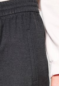 Mörkgrå joggingbyxor i texturerad kvalitet, med resårmidja och en sidficka med en ren, subtil sömdetalj.