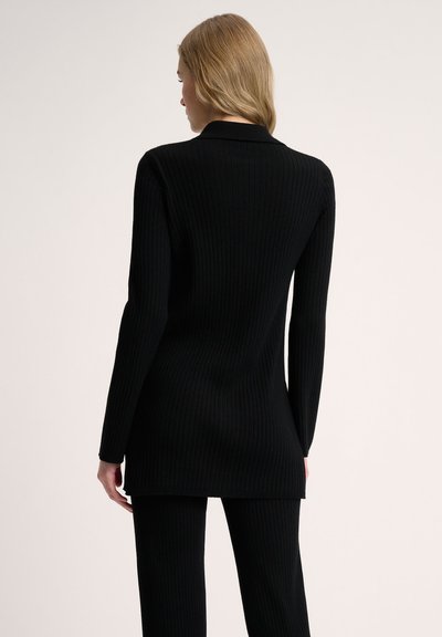 Black ribbed knit long-sleeve top with a collar, featuring a straight hem and fitted design, paired with matching ribbed pants.