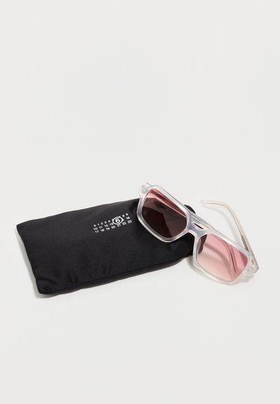 Διάφανα ορθογώνια γυαλιά ηλίου με ροζ φακούς, τοποθετημένα σε μαύρο υφασμάτινο πουγκί με λευκή αριθμητική εκτύπωση.