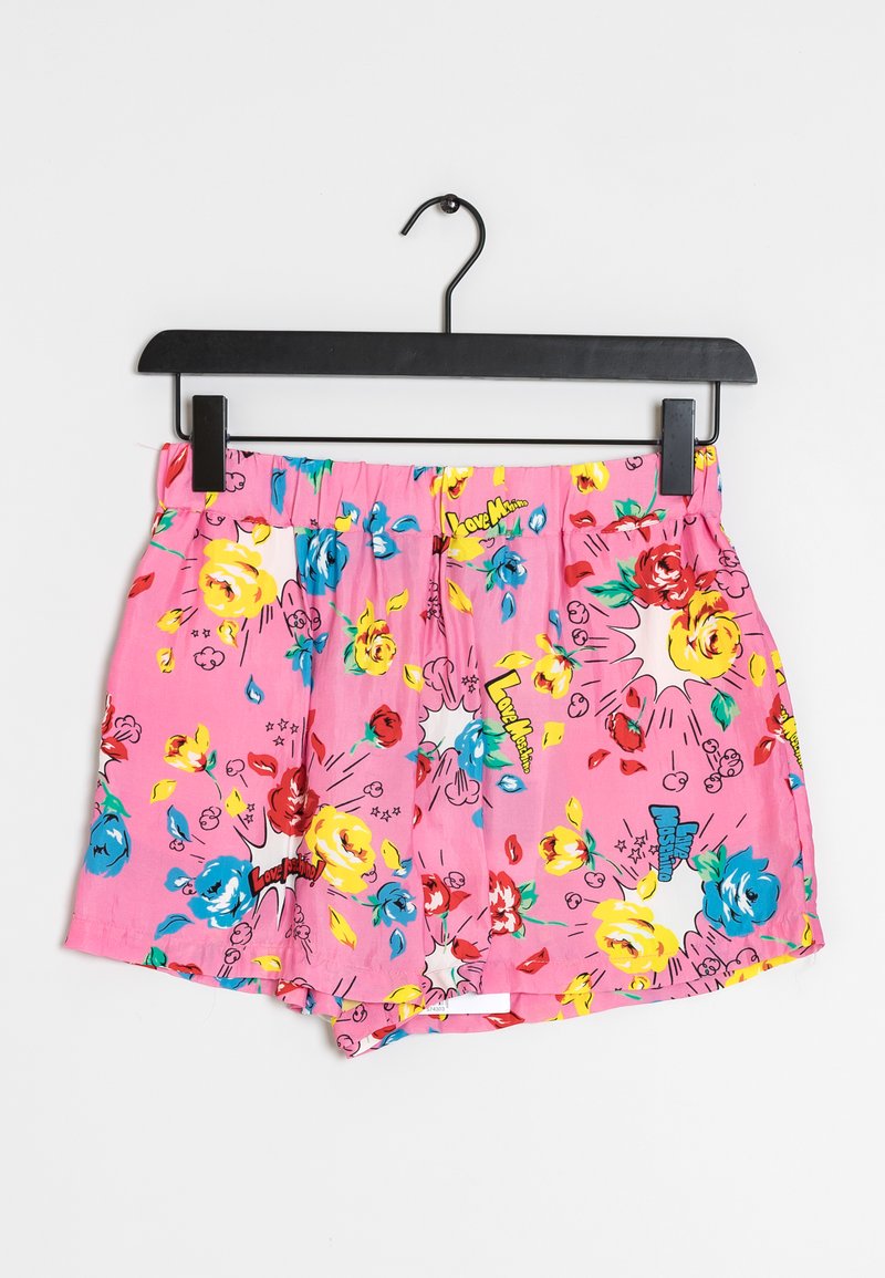 Shorts floraux roses avec un motif vibrant comportant des fleurs bleues, jaunes et rouges, une taille élastique et des coutures apparentes.