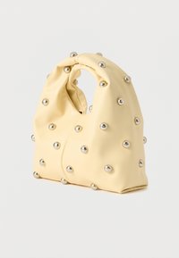 Κρεμ χρωματιστή μαλακή τσάντα με στρογγυλά ασημένια καρφιά, με λαβή που μαζεύει και δομημένο, ελαφρώς χαλαρό σχήμα.