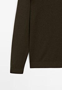 Braunes Langarmshirt aus einem weichen, strukturierten Stoff. Mit gerippten Bündchen und Saum, rundem Ausschnitt und leichten Seitenschlitzen am Saum.