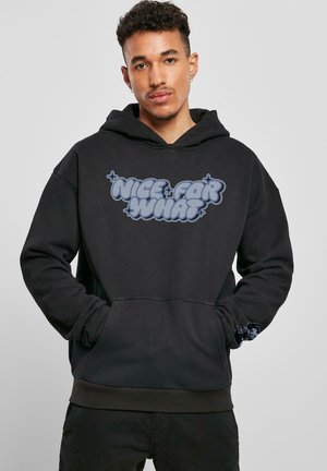 Sort hættebluse med løs pasform, stor frontlomme, struktureret stof og en "NICE FOR WHAT" grafik i blå. Har ribbet manchetter og kant.