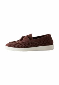 Chaussure slip-on en suede marron présentant une texture tissée, une semelle en caoutchouc blanc et un accent en nœud décoratif sur le devant.