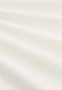 Tissu blanc texturé avec un motif géométrique subtil, présentant une surface douce et lisse et un tombé délicat, adapté pour le rembourrage ou l'habillement.