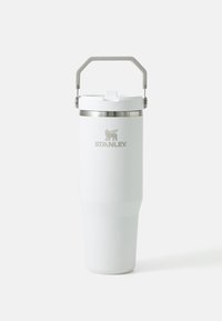 Mug de voyage en acier inoxydable blanc avec un corps effilé, un bord de couvercle argenté et une poignée grise. Présente un logo gravé à l'avant.