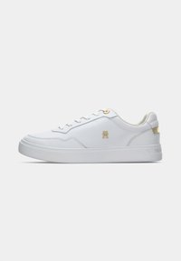 Sneaker bassa bianca con occhielli dorati, logo dorato sul lato e dettaglio dorato sul tallone, esposta su uno sfondo bianco semplice.