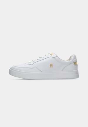 Sneaker bassa bianca con occhielli dorati, logo dorato sul lato e dettaglio dorato sul tallone, esposta su uno sfondo bianco semplice.