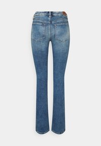 Blå denimjeans med lätt blekning från midjan till mitten av låren, bakfickor och en brun läderlogga på midjebandet.