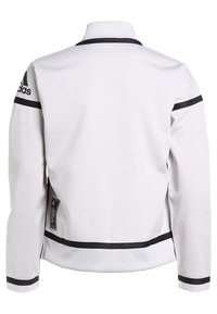 Weiße Sportjacke mit schwarzen Streifen, geripptem Kragen und markiertem Logo auf der linken Schulter. Verfügt über einen strukturierten Stoff und Seitentaschen.