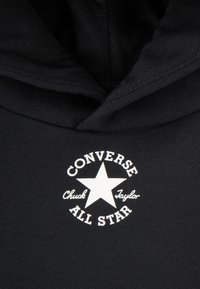 Black hoodie featuring a white round logo with a five-point star and text: "CONVERSE," "Chuck Taylor," and "ALL STAR." Soft fabric texture.