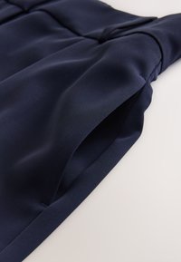 Primo piano di tessuto blu navy che mostra una tasca laterale su misura con una cucitura liscia e strutturata su un indumento.