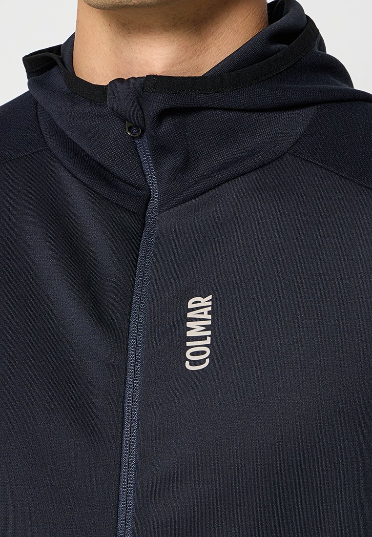 Felpa con zip di colore blu navy realizzata in un tessuto liscio e elastico. Presenta un colletto alto, dettagli testurizzati e un piccolo logo sul petto.