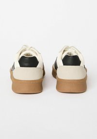White and black sneakers with suede heel accents and a textured gum sole. Soft lace-up design, featuring a smooth leather upper.