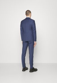 Navy blue suit jacket and trousers made of smooth fabric, tailored fit, back view, paired with black dress shoes.