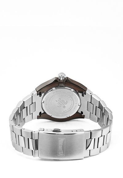 Silberner Edelstahl-Armbanduhr mit einem braunen Gehäuseboden, gemustertem Armband und einer Schnallenverschluss. Verfügt über eine strukturierten Oberfläche und eine Logogravur.