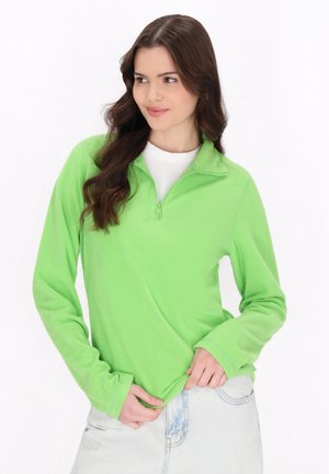 Hellgrüner Fleece-Pullover mit Reißverschlusskragen, langen Ärmeln, weicher Textur, kombiniert mit einem weißen Hemd und hellen Jeans.