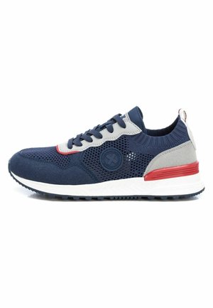 Zapatilla de deporte azul marino con materiales de malla y ante; presenta acentos grises, suela blanca y detalles rojos; puntera redondeada y parte superior texturizada.