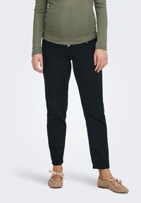 Melnas džinsa bikses ar štābiņu piegriezumu un vidēju vidukļa augstumu, kopā ar ribotu, ar garām piedurknēm, olīvu zaļu topu. Zamšādas dzīvokļi ar lokiem.