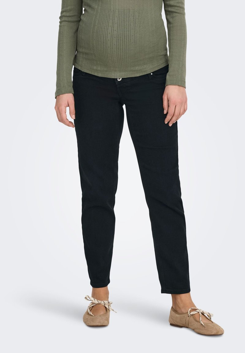 Melnas džinsa bikses ar štābiņu piegriezumu un vidēju vidukļa augstumu, kopā ar ribotu, ar garām piedurknēm, olīvu zaļu topu. Zamšādas dzīvokļi ar lokiem.