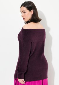 Maglione a spalle scoperte di colore viola scuro, realizzato in maglia con texture a coste e maniche lunghe, abbinato a una gonna rosa uniforme.