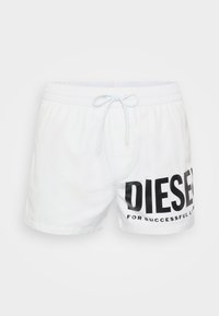 White swim shorts made of lightweight material featuring an elastic waistband with a drawstring and a large black "DIESEL" logo on the side.