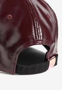 Burgundská lesklá kšiltovka s lesklým povrchem, černý nastavitelný pásek na zadní straně a metalický akcent na pásku.