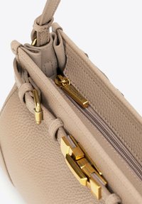 Sac à main en cuir beige avec une texture grainée, doté d'une fermeture éclair et d'accents en métal doré. L'intérieur comprend une poche zippée.