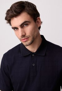 Pomorska modra polo majica z teksturiranim karo vzorcem, z ovratnikom, tremi gumbi in tesno prilegajočim se krojem.