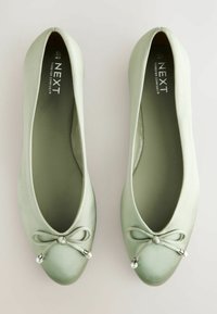 Zapatos planos de color verde claro con acabado satinado, punta redondeada, acento de lazo en la parte delantera y detalles metálicos. Nombre de la marca: NEXT.