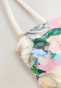 Blommönstrad handväska med en kanvaskropp. Utrustad med beige remmar och detaljer i guld. Färgerna inkluderar rosa, grön och blå.
